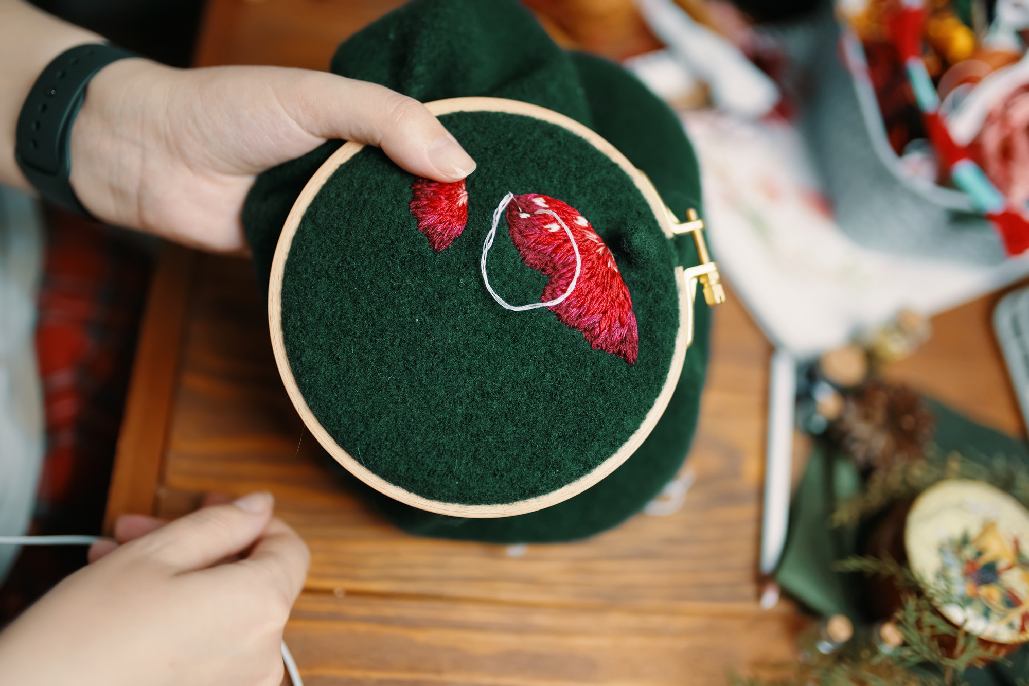 Close-up of hand-guided embroidery hoop with golden thread